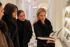 La docente Virginia Damtsa mostra un libro d'arte aperto agli studenti.