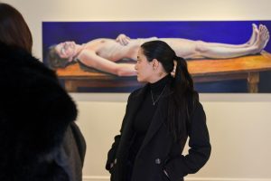 Studentessa osserva un dipinto colorato di una figura distesa da Lyndsey Ingram.