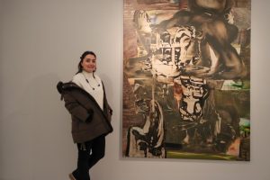 Donna accanto a un grande dipinto astratto in una galleria.