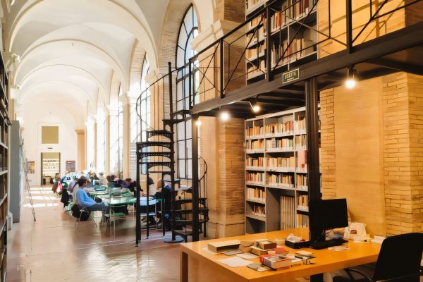 Studenti che studiano in una luminosa sala lettura con librerie e spazi di lavoro nel centro storico di Roma, vicino al Campus ESE.