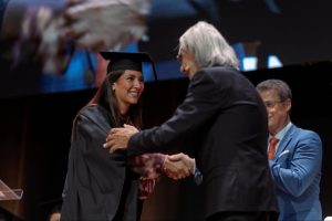 Un laureato riceve le congratulazioni sul palco da Elio D'Anna durante il conferimento dei titoli — Cerimonia di Laurea ESE, 4 luglio 2026.
